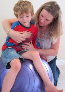 speech pathologist with child on ball signing more